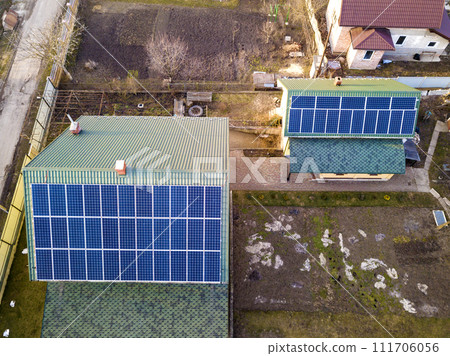 Aerial top view of new modern residential house cottage with blue shiny solar photo voltaic panels system on roof. Renewable ecological green energy production concept. Aerial top view of new modern residential house cottage with blue shiny solar photo voltaic panels system on roof. Renewable ecological green energy production concept. 111706056