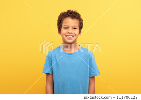 Portrait of smiling boy in blue shirt against yellow background 111706122