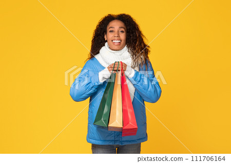 Happy black lady with colorful shopper bags on yellow background 111706164