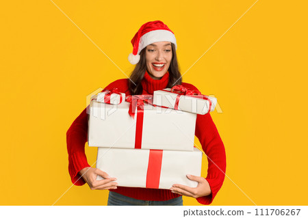 Excited woman holding many presents boxes on yellow studio background Excited woman holding many presents boxes on yellow studio background 111706267