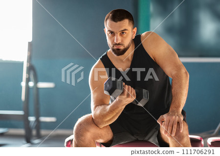 Motivated Muscular Man Training With Dumbbell In Modern Gym 111706291
