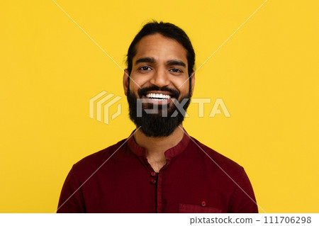Portrait of smiling handsome young indian man posing on yellow Portrait of smiling handsome young indian man posing on yellow 111706298