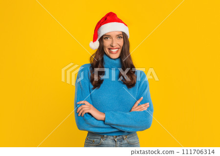 woman in Santa hat confidently crosses arms, yellow backdrop woman in Santa hat confidently crosses arms, yellow backdrop 111706314