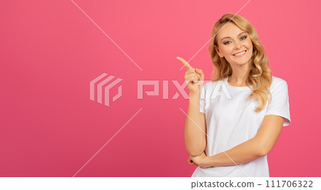 Positive Blonde Young Lady Pointing Finger Aside Over Pink Backdrop 111706322