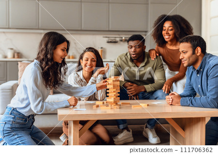 friends gathering around table engaging in lively board game indoor friends gathering around table engaging in lively board game indoor 111706362