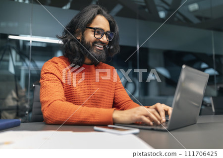 Successful bearded indian guy project manager sitting at workdesk 111706425