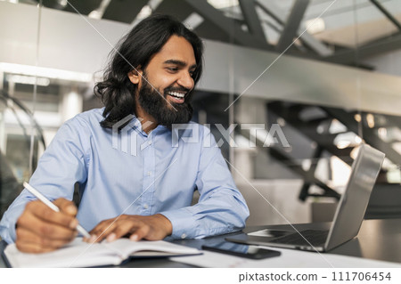 Handsome young indian businessman working with laptop computer at desk Handsome young indian businessman working with laptop computer at desk 111706454