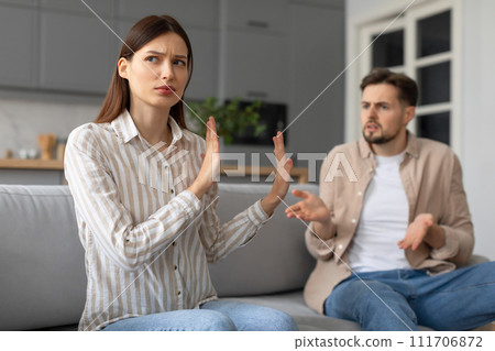 Spouses in heated argument at home, sitting on sofa Spouses in heated argument at home, sitting on sofa 111706872