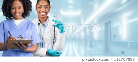 Two professional female nurses, one in blue scrubs writing on a clipboard 111707098