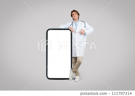 Doctor in lab coat leaning on a large phone, pointing at blank screen Doctor in lab coat leaning on a large phone, pointing at blank screen 111707314