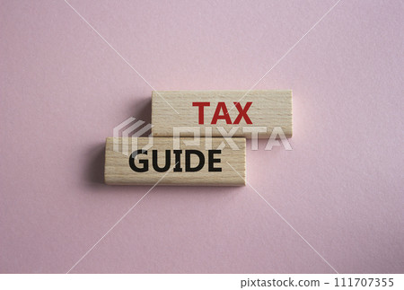 Tax Guide symbol. Concept word Tax Guide on wooden blocks. Beautiful pink background. Business and Tax Guide concept. Copy space Tax Guide symbol. Concept word Tax Guide on wooden blocks. Beautiful pink background. Business and Tax Guide concept. Copy space 111707355