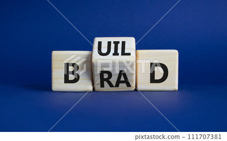 Build your brand symbol. Wooden cubes with words Build and Brand. Beautiful deep blue background. Build your brand and business concept. Copy space Build your brand symbol. Wooden cubes with words Build and Brand. Beautiful deep blue background. Build your brand and business concept. Copy space 111707381