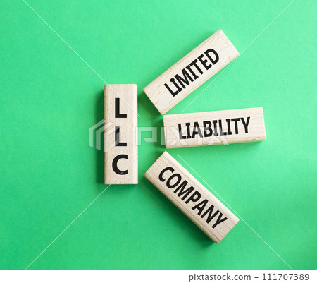 LLC - Limited liability company. Wooden cubes with word LLC. Beautiful green background. Business and LLC concept. Copy space. LLC - Limited liability company. Wooden cubes with word LLC. Beautiful green background. Business and LLC concept. Copy space. 111707389