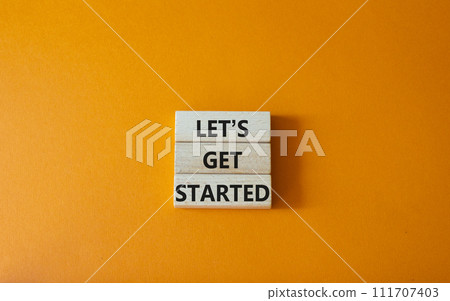 Lets get started symbol. Concept words Lets get started on wooden blocks. Beautiful orange background. Business and Lets get started concept. Copy space. 111707403