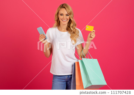 blonde lady shopping holding credit card and mobile phone, studio blonde lady shopping holding credit card and mobile phone, studio 111707428