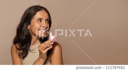 Glad caucasian senior woman make facial massage with quartz petal, look at copy space Glad caucasian senior woman make facial massage with quartz petal, look at copy space 111707481