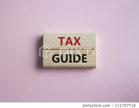 Tax Guide symbol. Concept word Tax Guide on wooden blocks. Beautiful pink background. Business and Tax Guide concept. Copy space 111707516