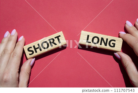 Short vs Long symbol. Concept word Short vs Long on wooden blocks. Businessman hand. Beautiful red background. Business and Short vs Long concept. Copy space Short vs Long symbol. Concept word Short vs Long on wooden blocks. Businessman hand. Beautiful red background. Business and Short vs Long concept. Copy space 111707543