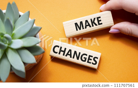 Make changes symbol. Wooden blocks with words Make changes with succulent plant. Beautiful orange background. Businessman hand. Business and Make changes concept. Copy space. 111707561