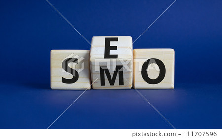 SEO vs SMO symbol. Wooden cubes with words SMO and SEO. Beautiful deep blue background. SEO vs SMO and business concept. Copy space 111707596
