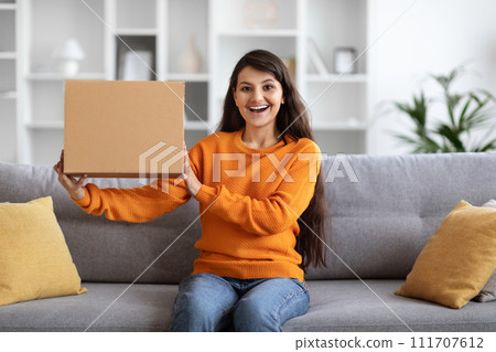 Excited indian woman customer holding big box parcel, home interior Excited indian woman customer holding big box parcel, home interior 111707612
