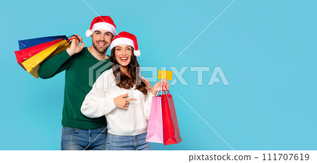 couple with Santa hats and bags holding credit card, studio 111707619
