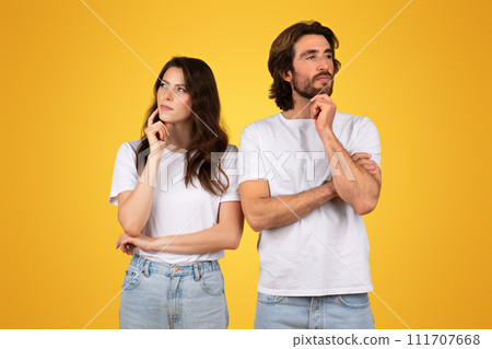 Pensive couple in white t-shirts and blue jeans, standing back-to-back with thoughtful expressions Pensive couple in white t-shirts and blue jeans, standing back-to-back with thoughtful expressions 111707668