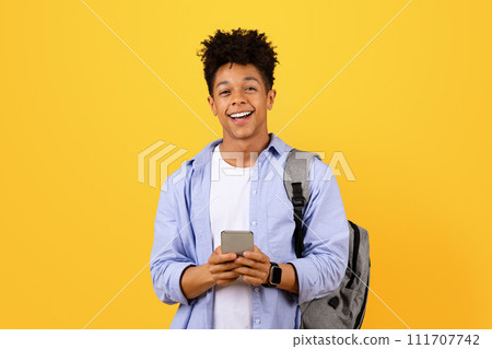 Happy black man student texting on phone with a backpack 111707742