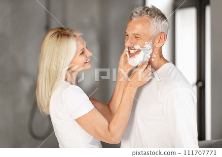 Caring Happy Mature Woman Helping Her Husband Shaving Face In Bathroom Caring Happy Mature Woman Helping Her Husband Shaving Face In Bathroom 111707771