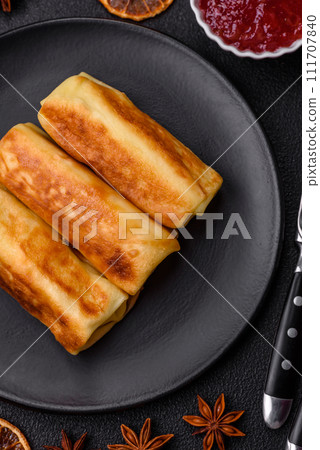 Delicious fried pancakes with filling rolled on a dark concrete background Delicious fried pancakes with filling rolled on a dark concrete background 111707840