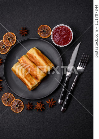 Delicious fried pancakes with filling rolled on a dark concrete background Delicious fried pancakes with filling rolled on a dark concrete background 111707844