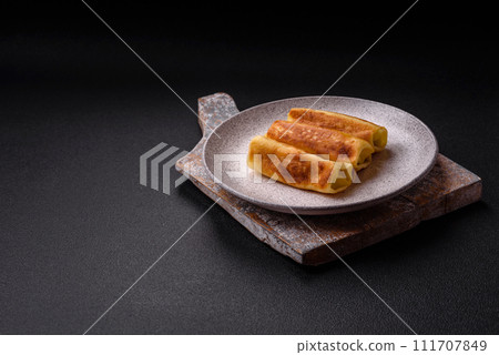 Delicious fried pancakes with filling rolled on a dark concrete background 111707849