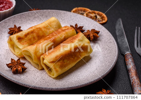 Delicious fried pancakes with filling rolled on a dark concrete background Delicious fried pancakes with filling rolled on a dark concrete background 111707864