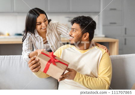 Loving indian wife surprising her husband with gift at home Loving indian wife surprising her husband with gift at home 111707865