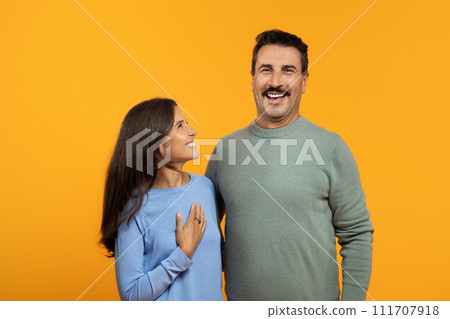 A joyful woman and man, dressed in casual clothing, laugh together 111707918
