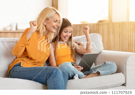 Excited grandmother and granddaughter using digital tablet at home Excited grandmother and granddaughter using digital tablet at home 111707929