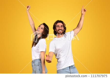 Energetic and happy young couple in white t-shirts and blue jeans joyously dancing 111707975