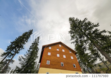 Two story wooden house cottage made of boards and logs on blue sky background. Two story wooden house cottage made of boards and logs on blue sky background. 111707980