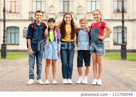 Multiethnic children with backpacks posing together outdoors 111708040