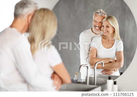Romantic Senior Couple Looking At Mirror And Cuddling In Bathroom 111708125