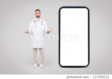 Happy doctor presenting giant smartphone with blank screen 111708131