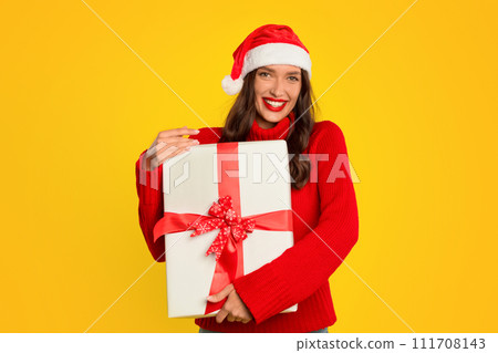 woman joyfully hugs wrapped gift box on yellow studio background woman joyfully hugs wrapped gift box on yellow studio background 111708143