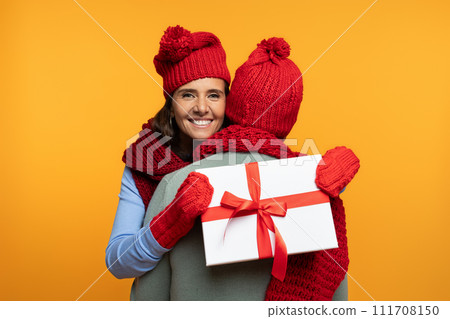 Cheerful senior european wife in hat hug husband at winter, gift box present Cheerful senior european wife in hat hug husband at winter, gift box present 111708150