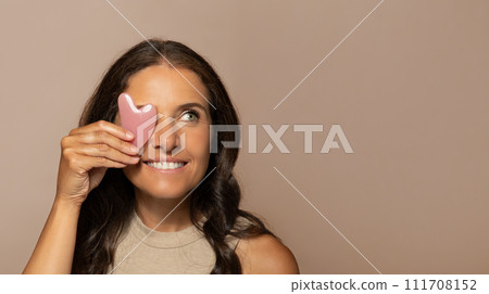 Smiling european senior woman put quartz petal to eye, enjoy natural beauty care massage Smiling european senior woman put quartz petal to eye, enjoy natural beauty care massage 111708152
