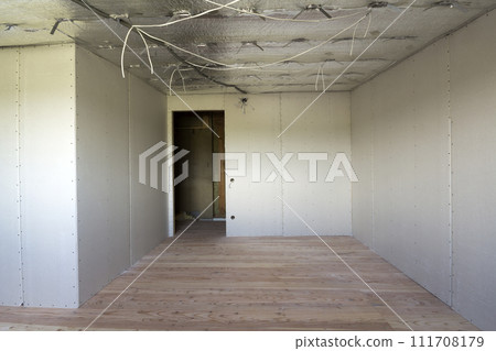 Room under construction with silver aluminum insulation foil and drywall on walls and ceiling. 111708179