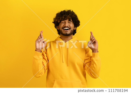 Superstitious indian guy with closed eyes and crossed fingers 111708194