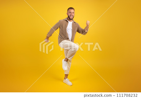 Cheerful young caucasian guy with beard in casual has fun, dance, jumping, freezes in air 111708232