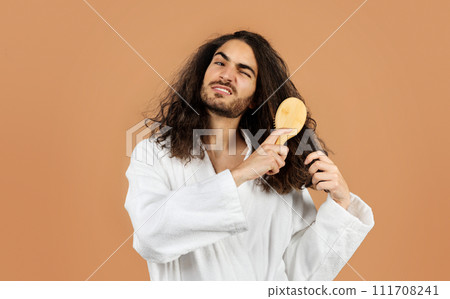 young man combs through curly hair suffering from pain, studio young man combs through curly hair suffering from pain, studio 111708241