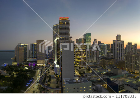 Downtown district of Miami Brickell in Florida. Skyline with illuminated high skyscraper buildings and street with cars and Metrorail traffic in modern american megapolis 111708333