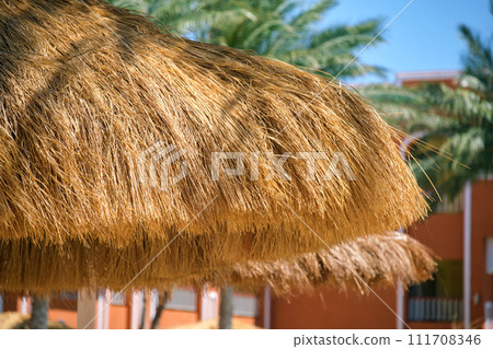 Detail of straw shade umbrellas on seaside in tropical resort. Summer vacations and getaway concept 111708346